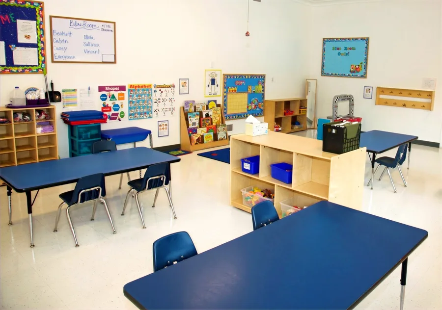 The Blue Room set up for the afternoon, with navy tables and chairs and the group's names posted on the board above them.